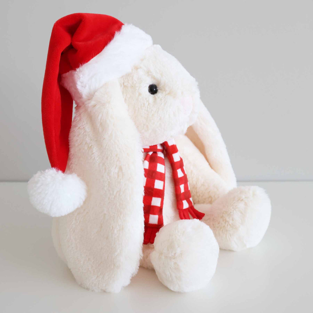 side view of christmas bunny stuffed animal wearing a red santa hat and red and white checkered scarf