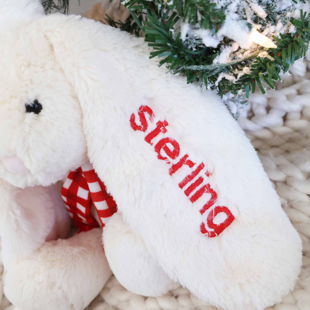 closeup of white bunny stuffed animal with embroidered name on the ear in red thread 