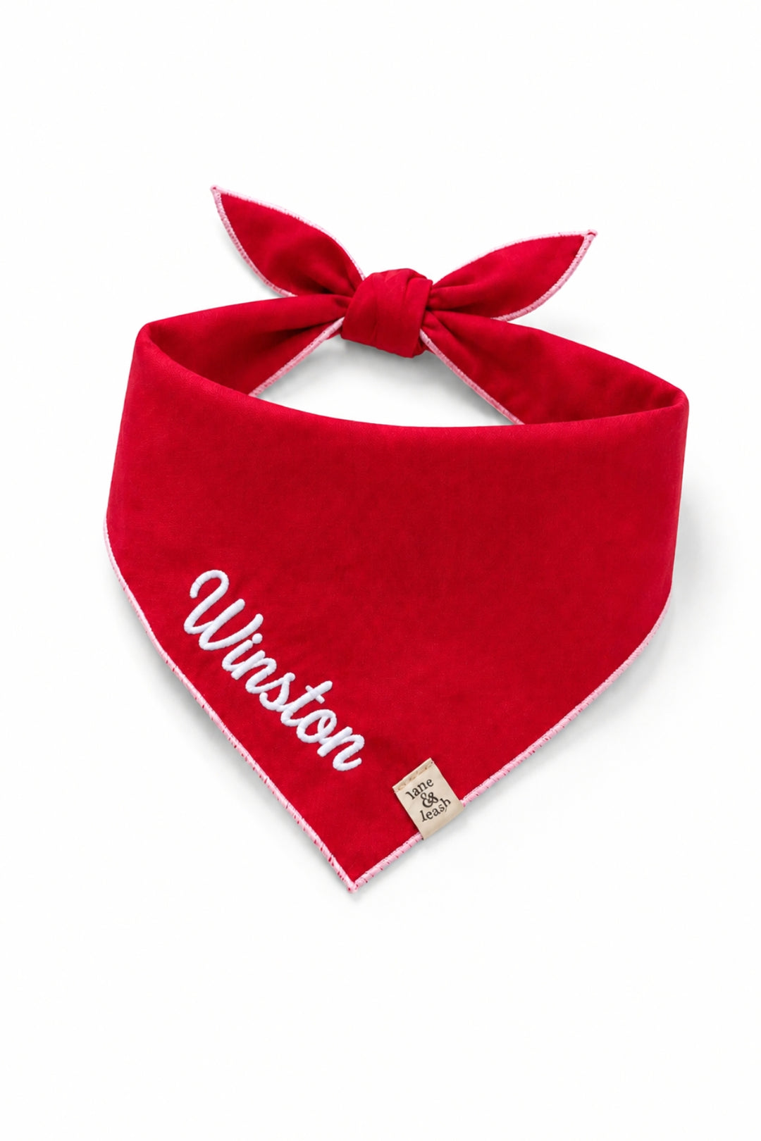 Lane & Leash personalized dog bandana in solid red with white stitched edging, tied bandana-style, embroidered with the name 'Winston' in white script