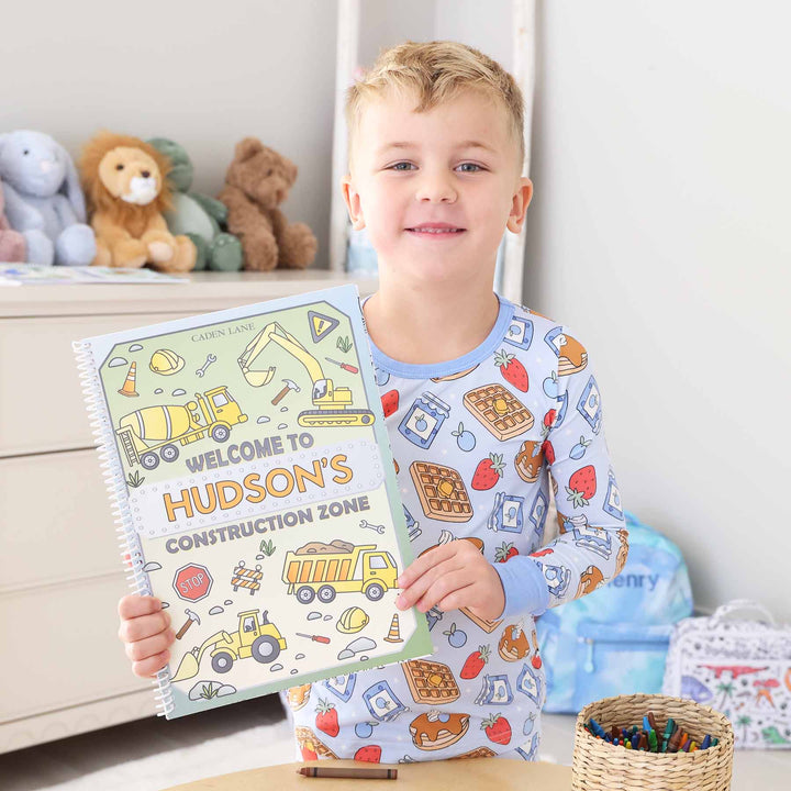 boy holding personalized construction themed coloring book 