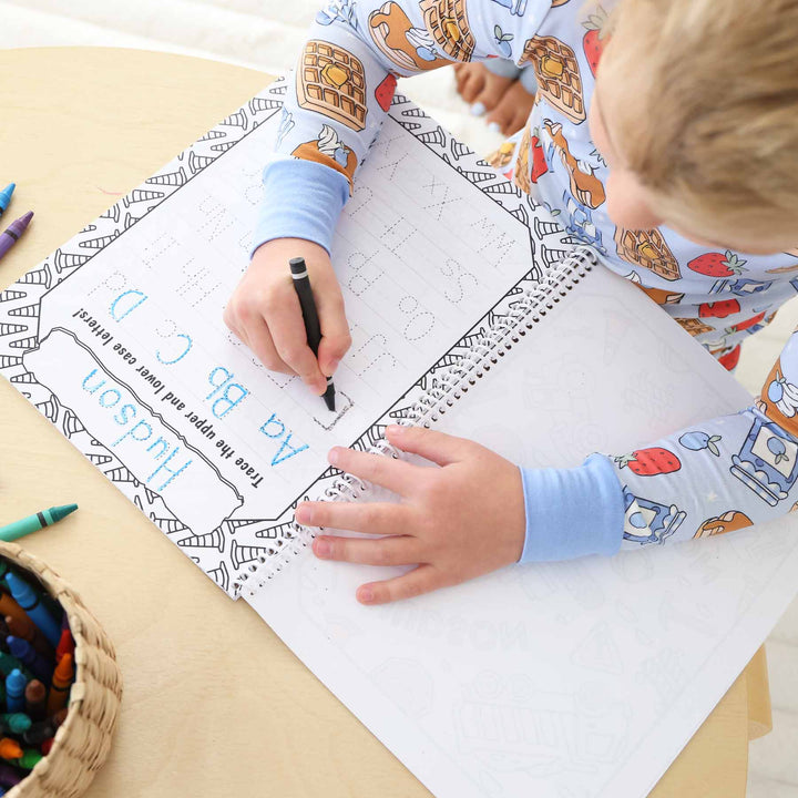 boy tracing letters in personalized coloring book 