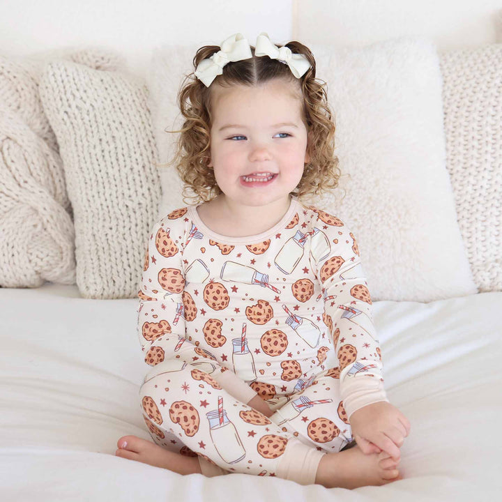 girl sitting on a bed wearing cookie cuddles pajama 