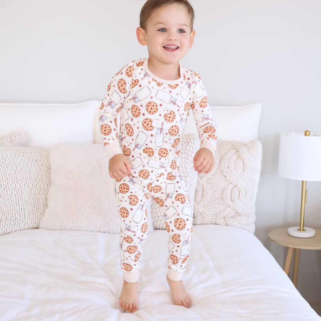 boy jumping on a bed wearing milk and cookies two piece pajama set 
