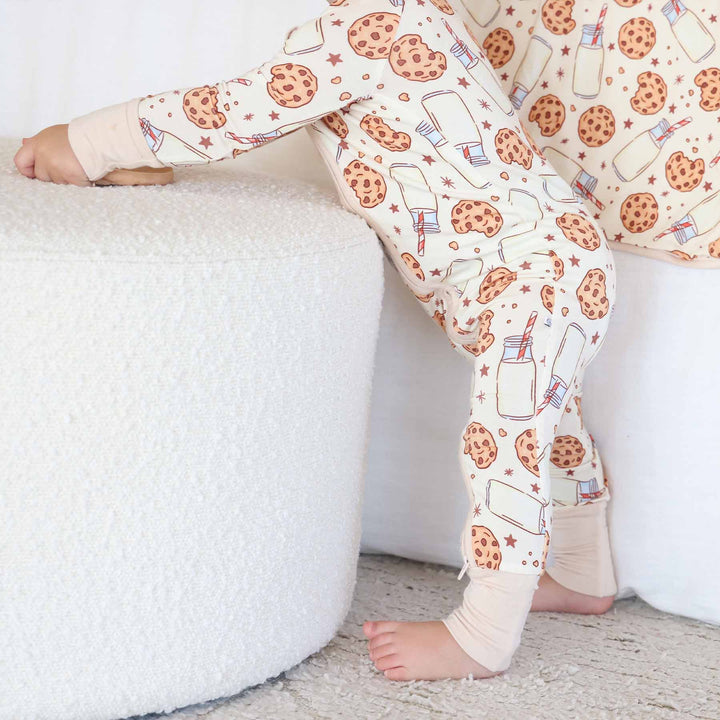 Side profile of baby standing while wearing the Cookie Cuddles Convertible Zip Romper