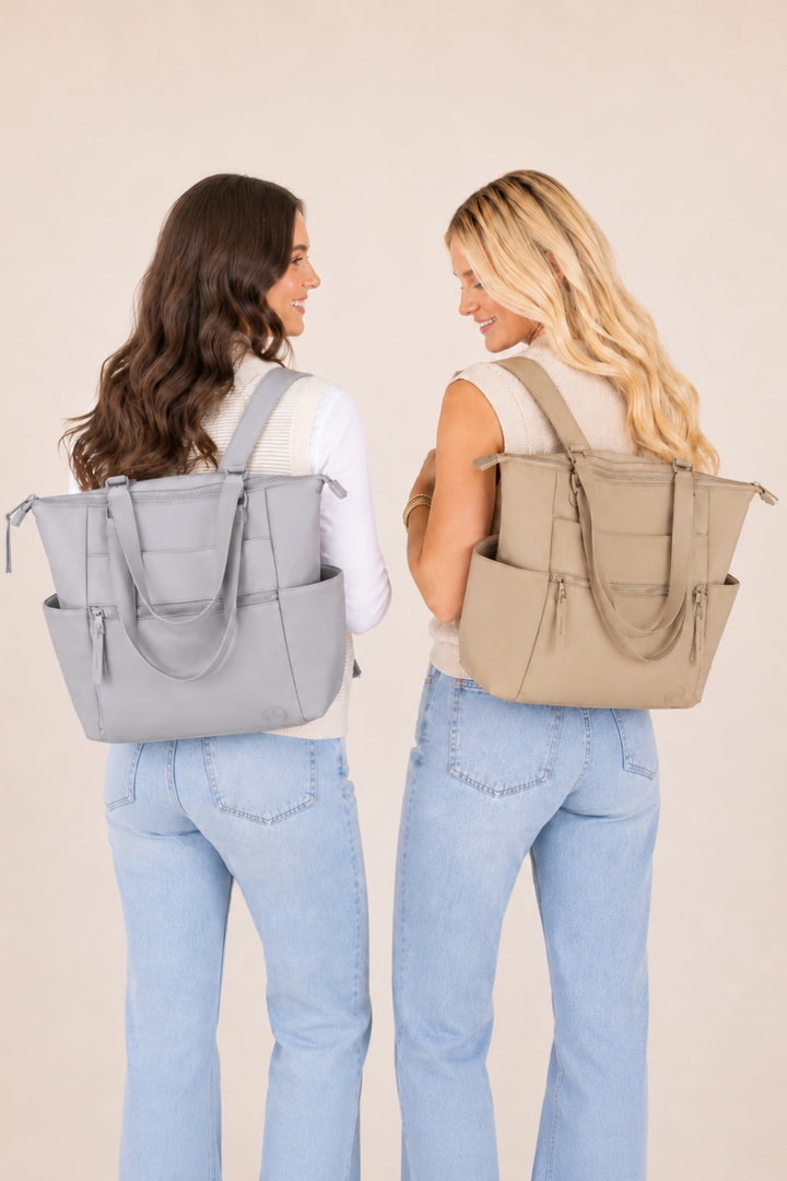 Two women shown from the back wearing large tote backpacks in light gray and beige, paired with light blue jeans, against a plain beige studio background.