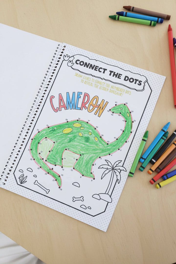 Personalized 'Cameron' connect-the-dots activity page from a Caden Lane Dinosaur Coloring Book, partially completed with red crayon revealing a hidden dinosaur shape