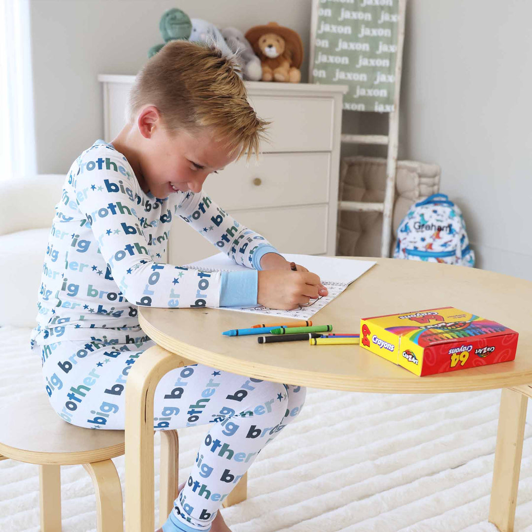 boy sitting at a table coloring a coloring book