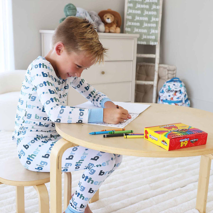 boy sitting at a table coloring a coloring book