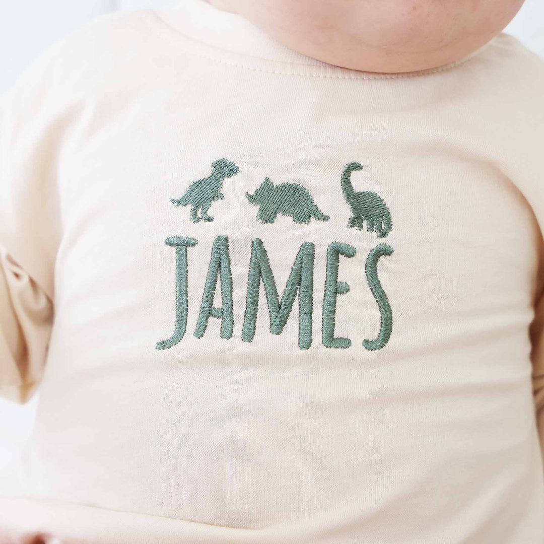 natural tan green thread dinosaur and name embroidered long sleeve bubble romper for babies and toddlers