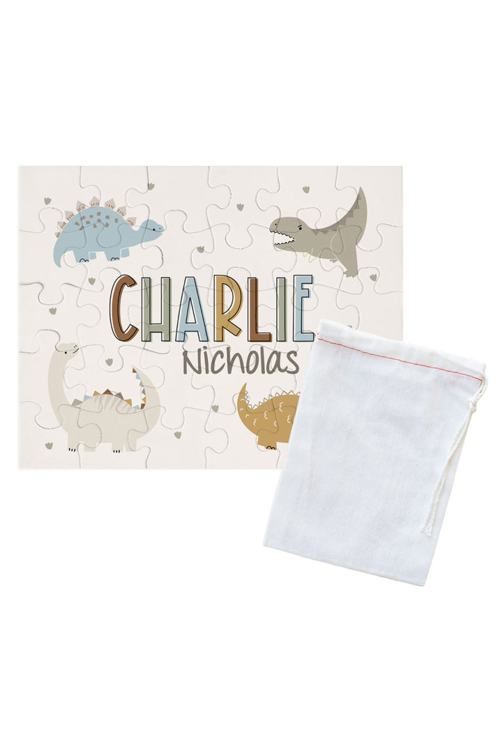 Personalized Caden Lane Dino Stomps jigsaw puzzle in cream, showing dinosaurs and custom name, paired with a white drawstring storage bag