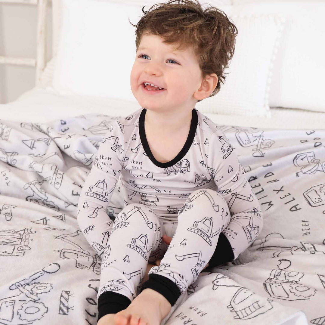 boy wearing printed kids bamboo pajama set with construction truck doodle art