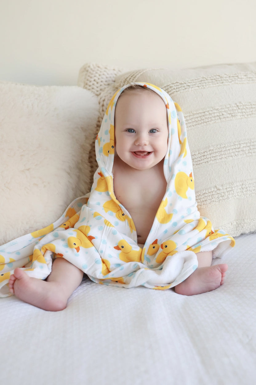 smiling baby wrapped in rubber duck towel