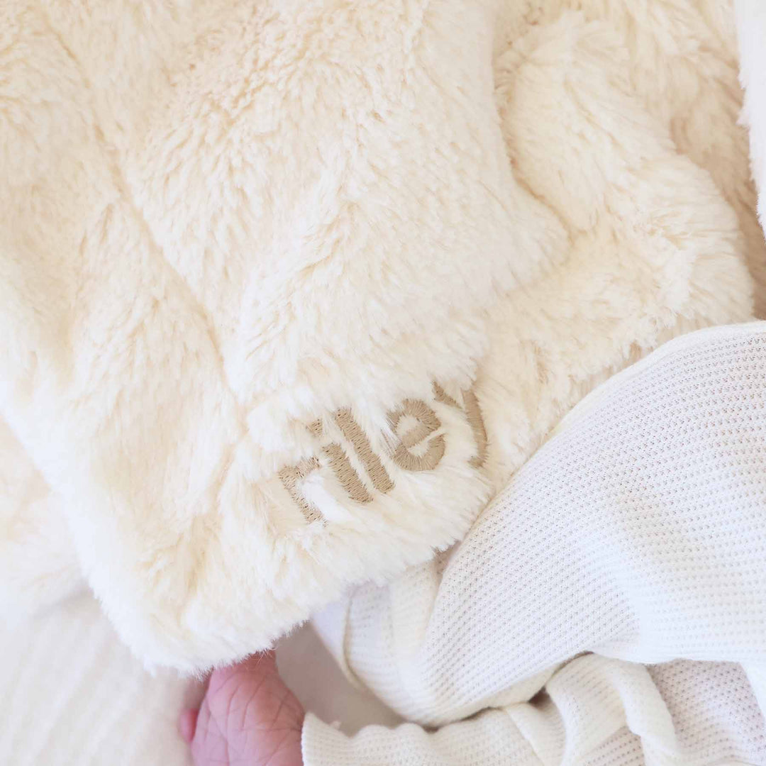 closeup of white bunny lovey for babies embroidered with name in neutral thread and block font 