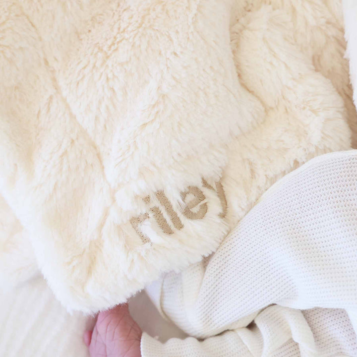 closeup of white bunny lovey for babies embroidered with name in neutral thread and block font 