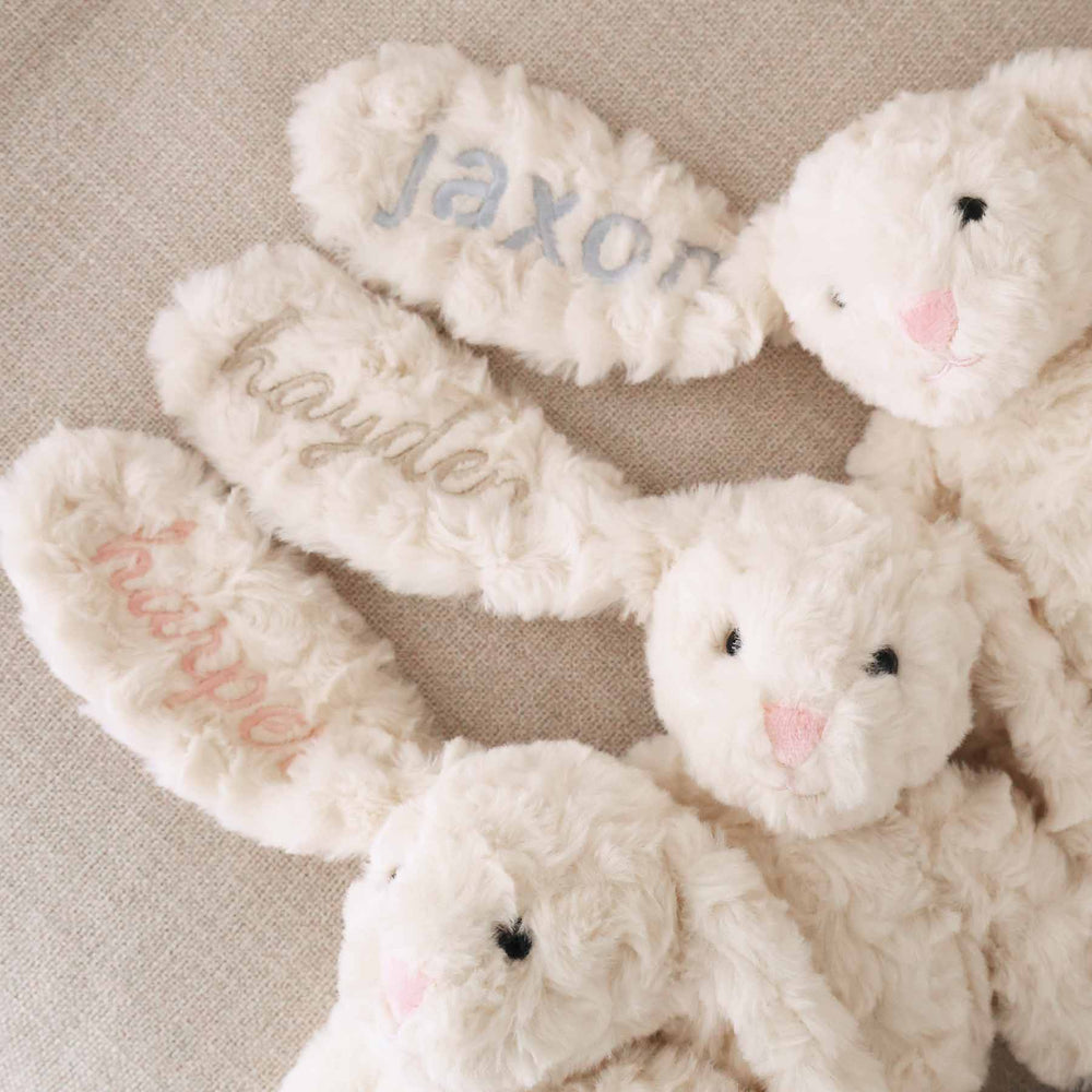 3 personalized stuffed animal bunnies with names embroidered on them in block and script fonts