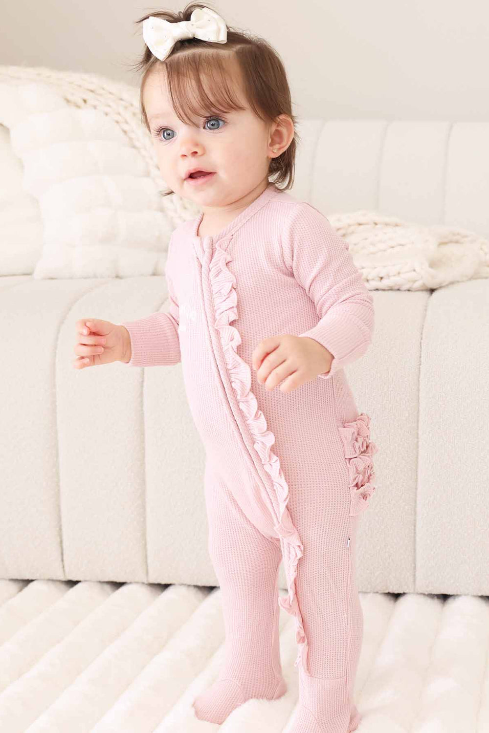 white thread embroidered name footie for baby girls with ruffles on the bottom