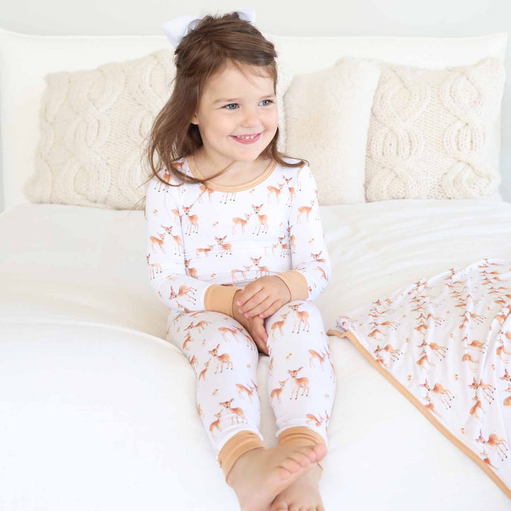 girl wearing a long sleeve and pant two piece pajama set with deer and mushroom 