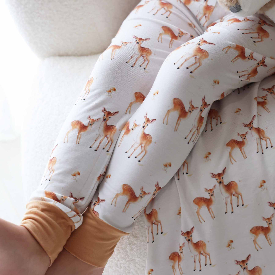 Boy in soft woodland pajama set posing with a coordinating deer stuffed toy