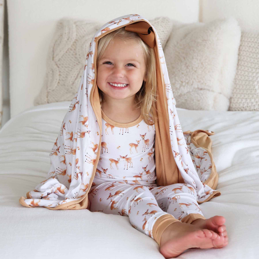 girl wearing fawn long sleeve two piece pajama set with bamboo blanket on top of her head 