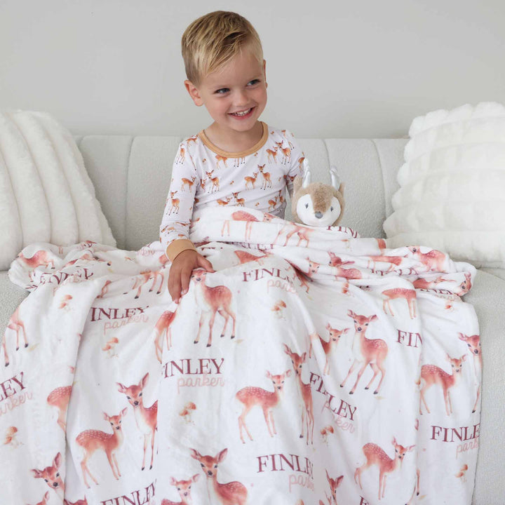 boy wearing deer pajama covered in matching personalized blanket 