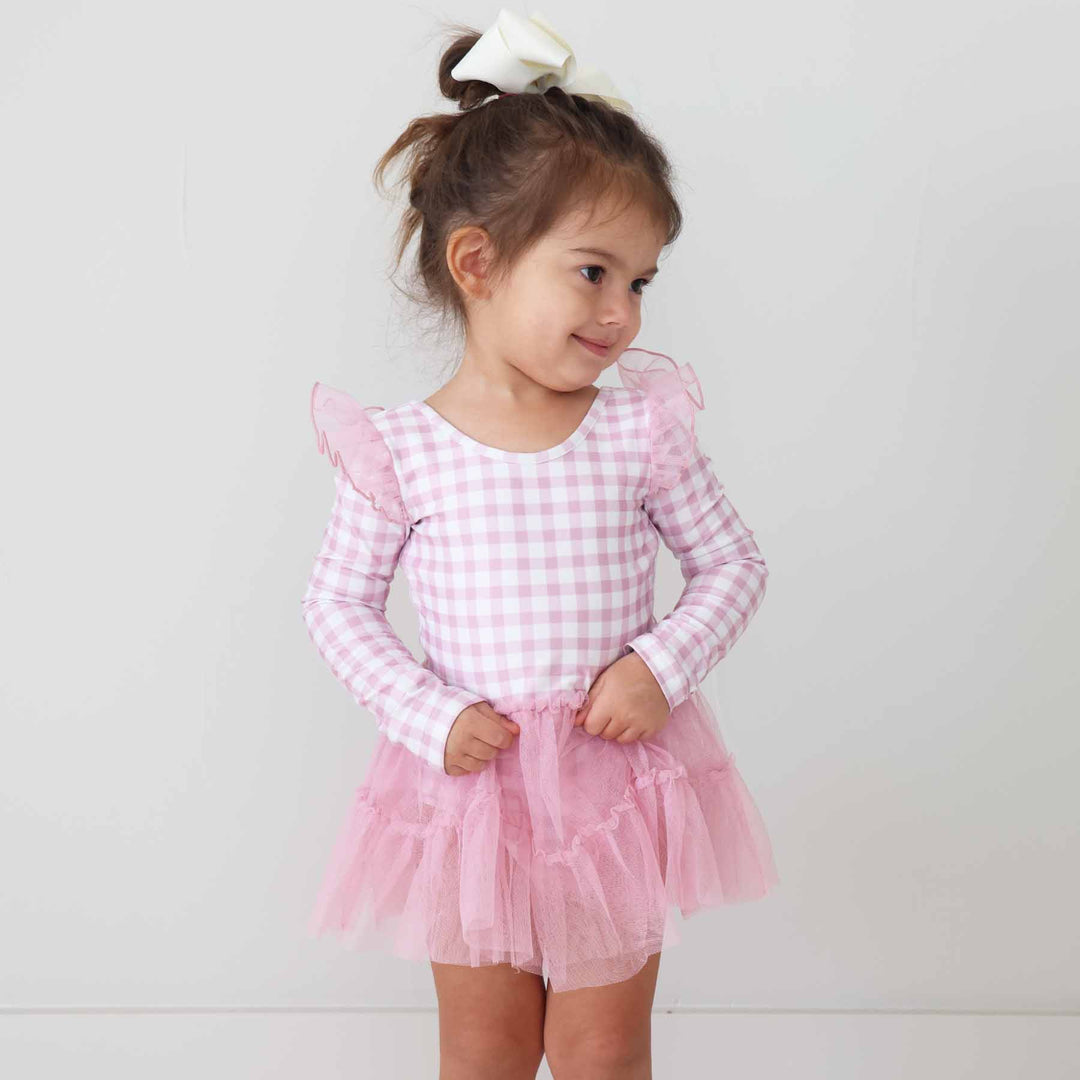 toddler girl wearing a long sleeve pink and white gingham leotard with a pink tulle skirt 