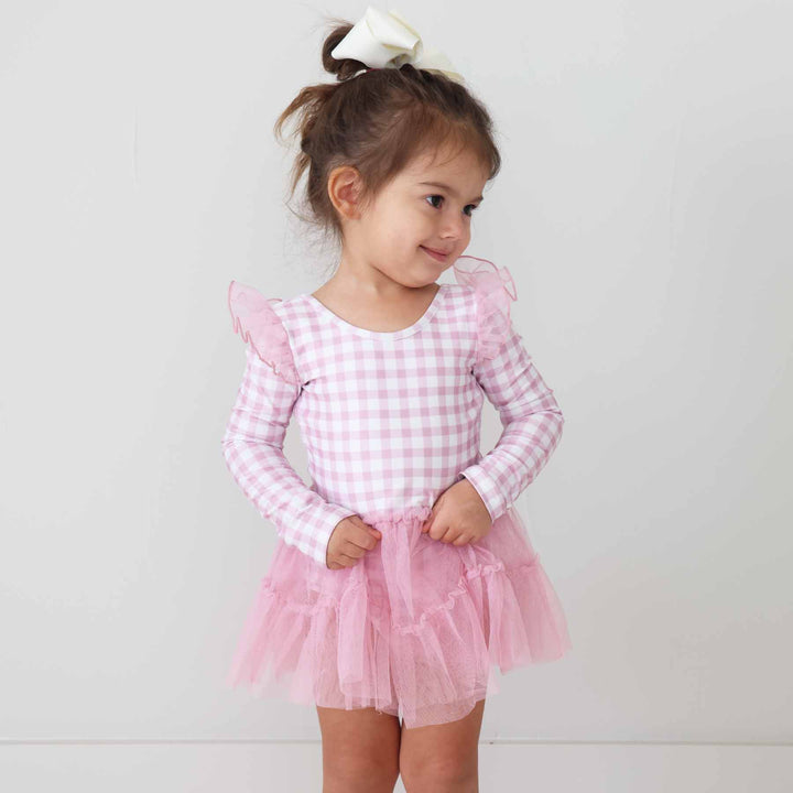 toddler girl wearing a long sleeve pink and white gingham leotard with a pink tulle skirt 