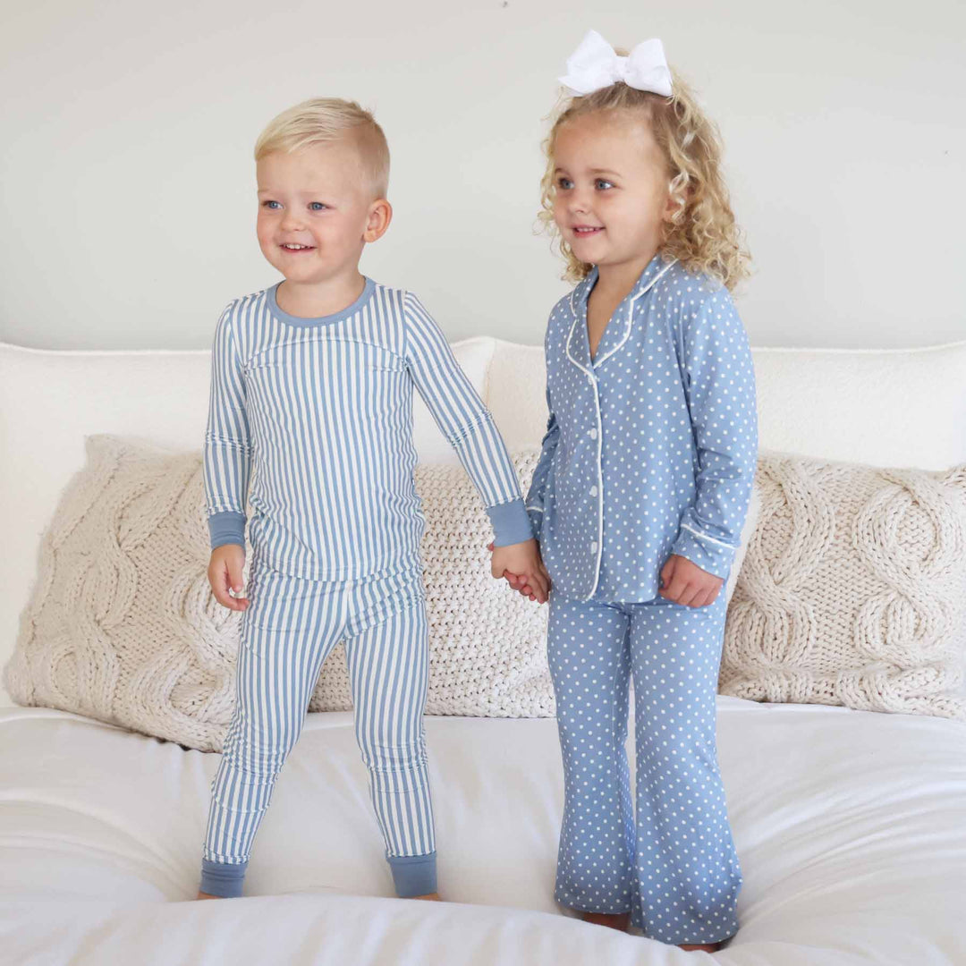 boy wearing a blue and white stripe pajama set holding hands with girls wearing a coordinating long sleeve lounge set that is blue with white polka dots 