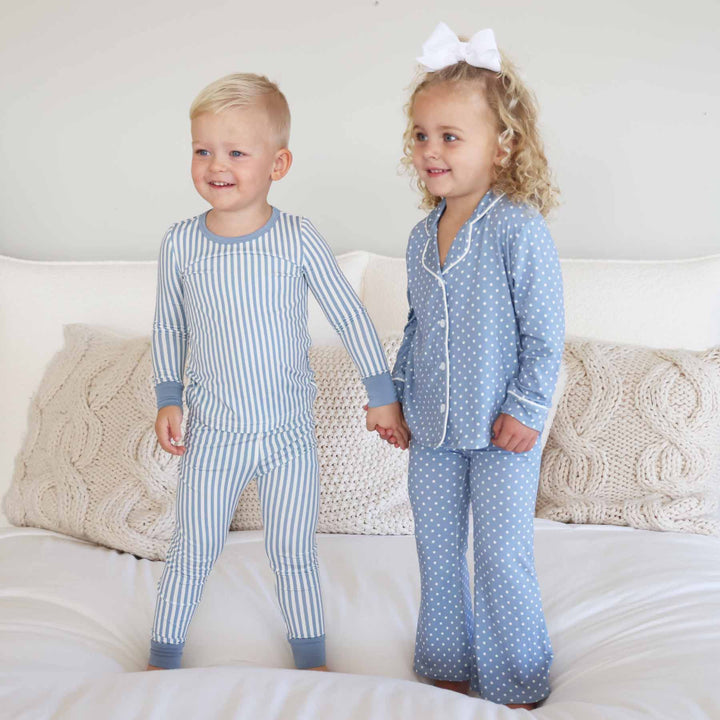 boy wearing a blue and white stripe pajama set holding hands with girls wearing a coordinating long sleeve lounge set that is blue with white polka dots 