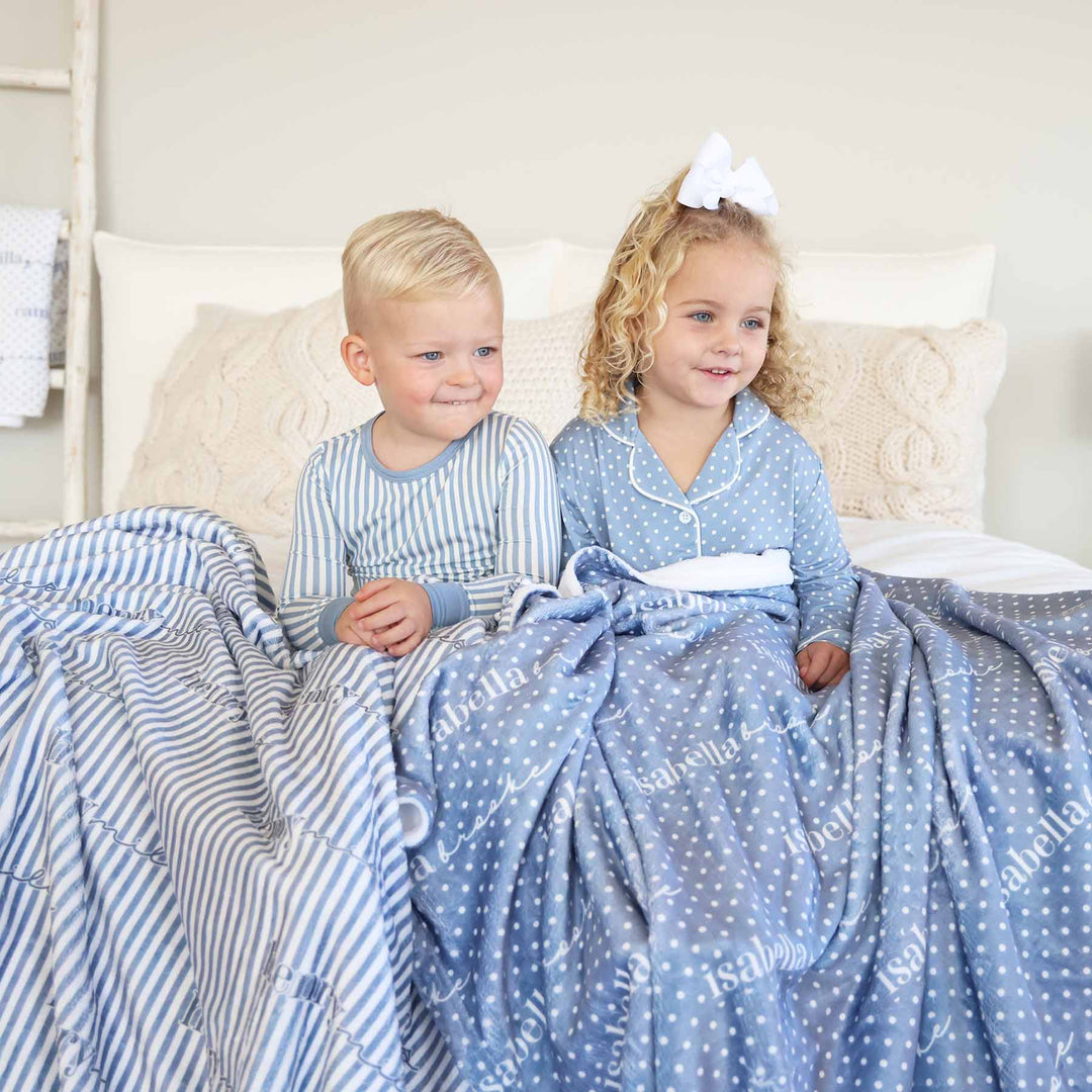 sibling matching pajama and lounge sets. boy is wearing a blue and white stripe long sleeve pajama set and girl is wearing a long sleeve lounge set with polka dots.