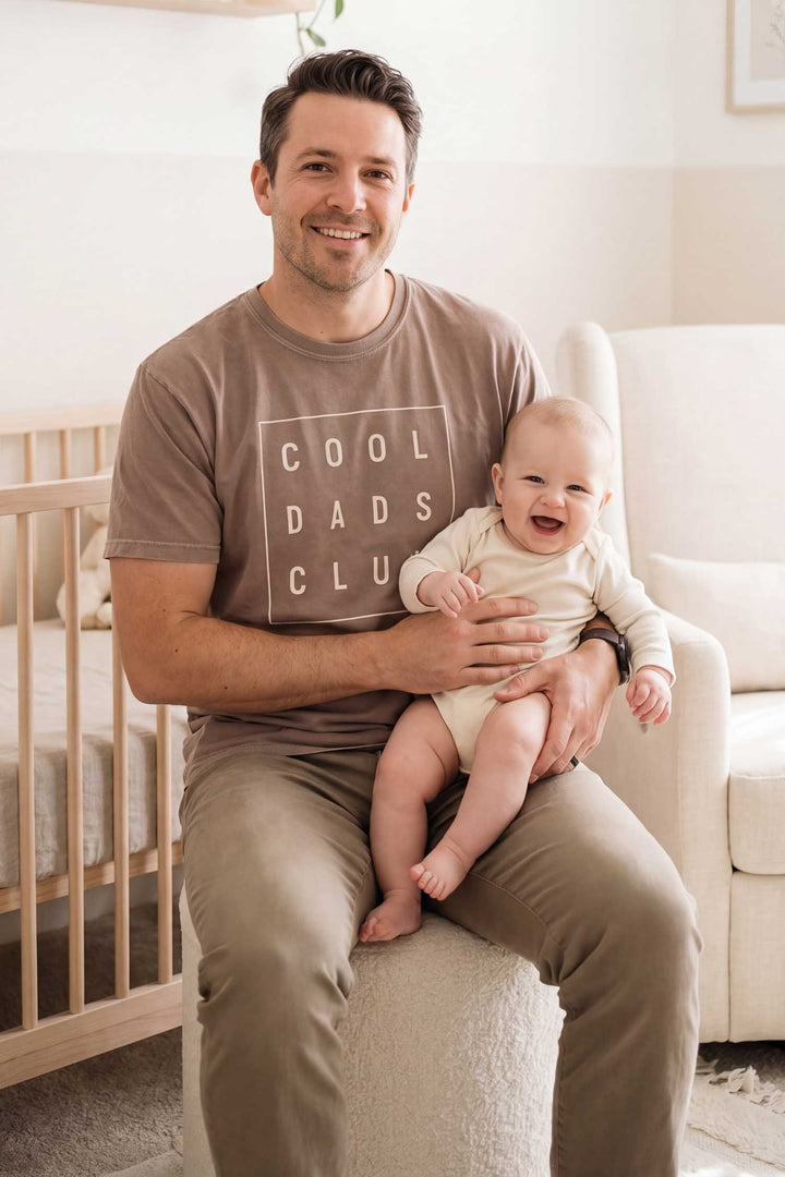 dad holding baby wearing the cool dads club graphic tee