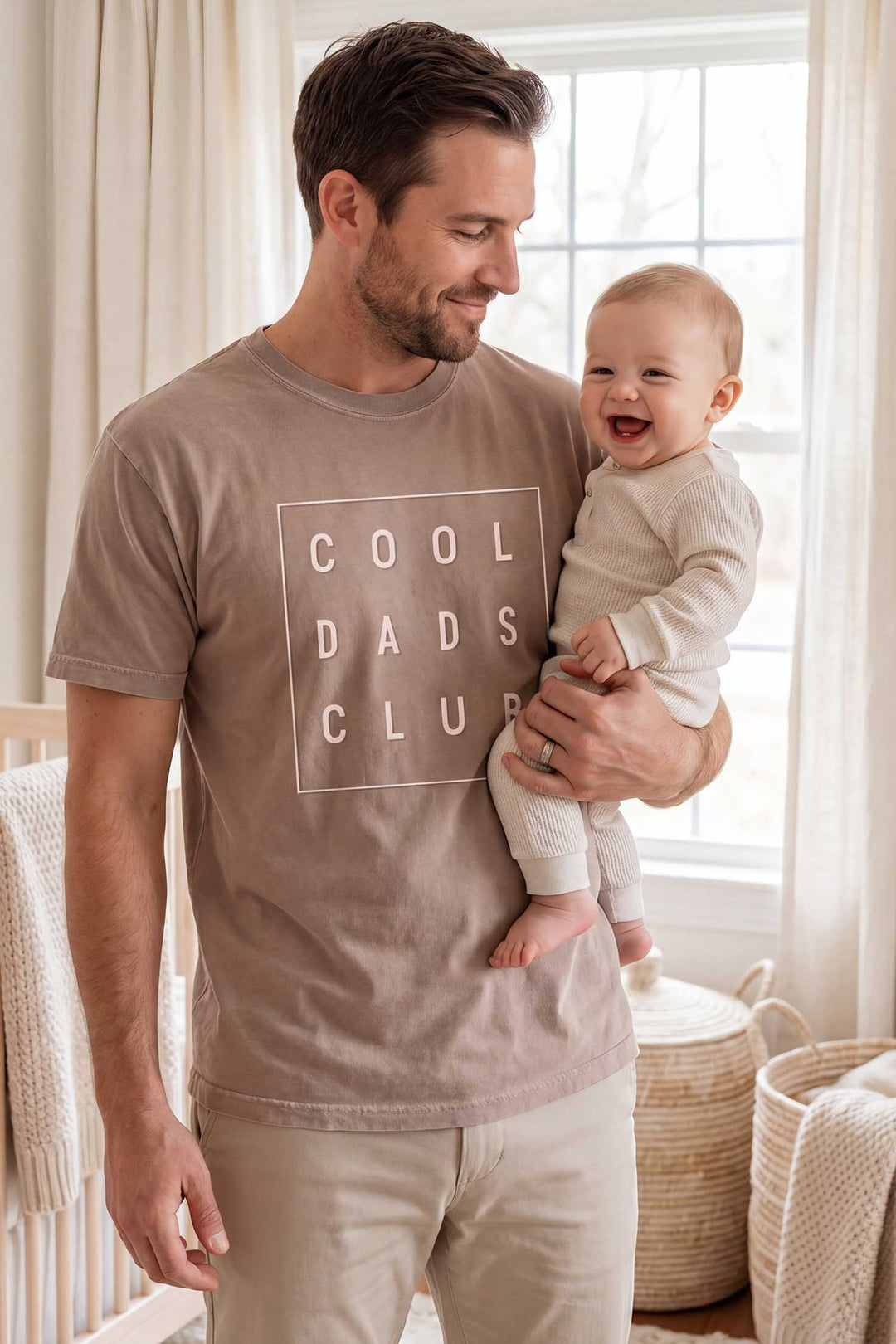 dad holding baby wearing the cool dads club graphic tee