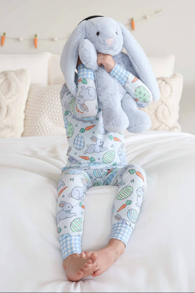 boy wearing pastel blue easter pajama set holding a large blue stuffed bunny 