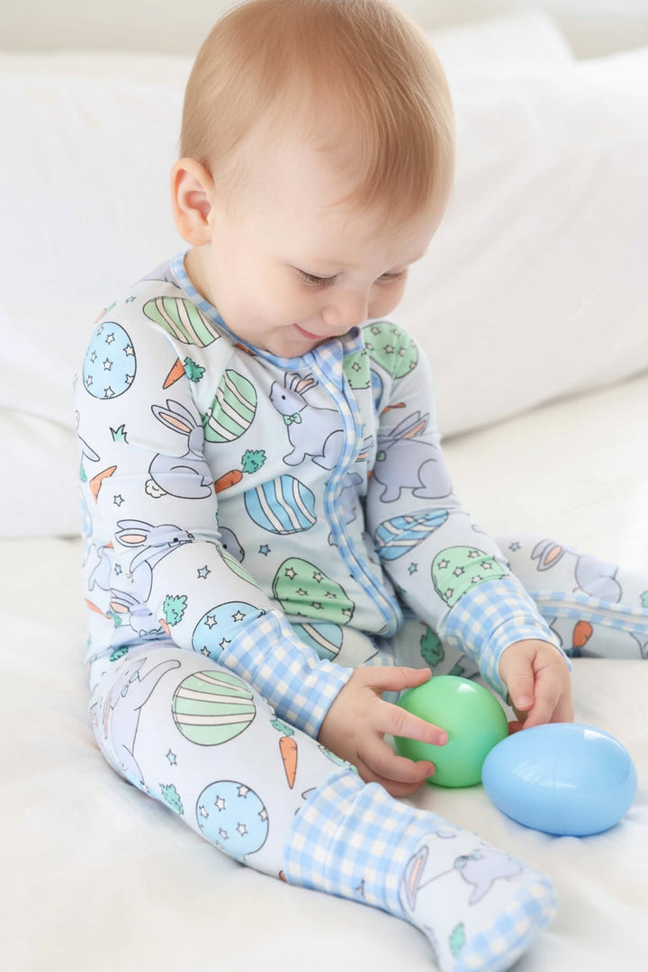closeup of baby boy wearing hoppy spring convertible zip romper pajama playing with blue and green easter eggs