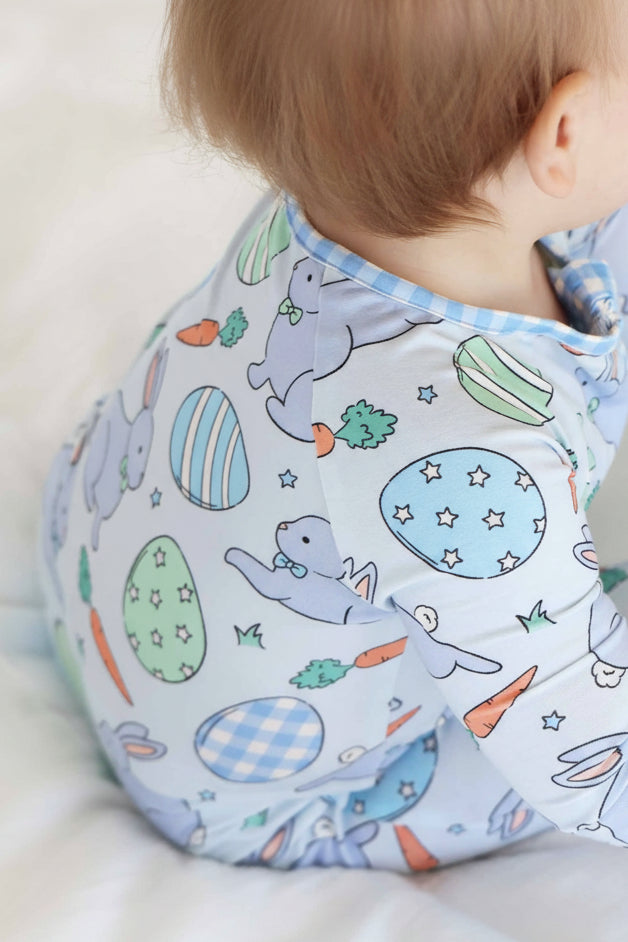 closeup of blue hoppy spring easter pajama print with printed easter eggs, blue bunnies, carrots and stars 
