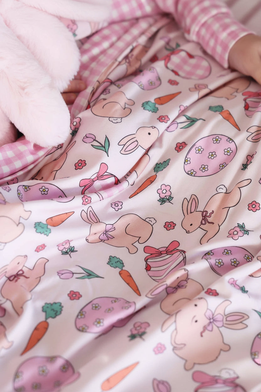 closeup of pink hoppy spring double sided bamboo blanket with bunnies, easter eggs, carrots and flowers 