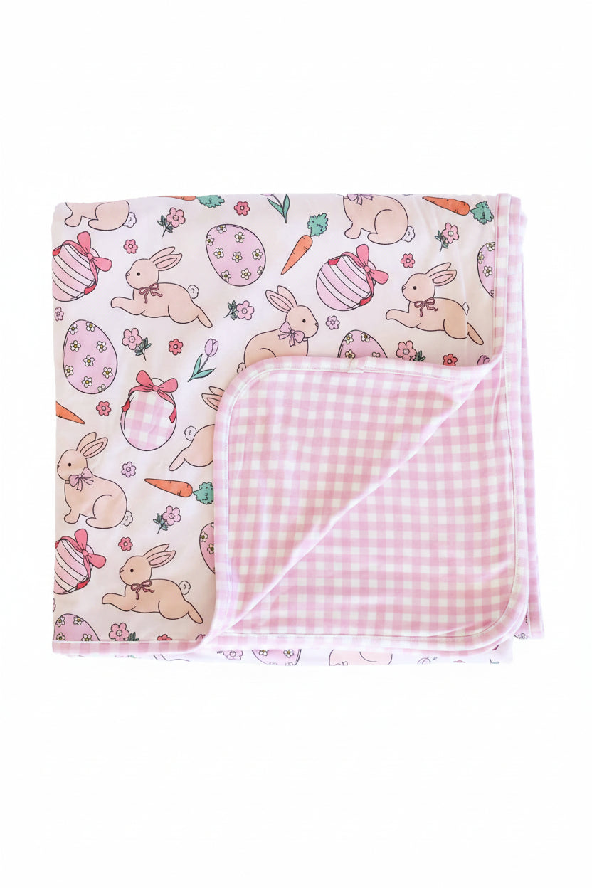 pastel pink bunny, easter egg, bunny and flower easter bamboo blanket for kids with a pink and gingham print on the reverse side 