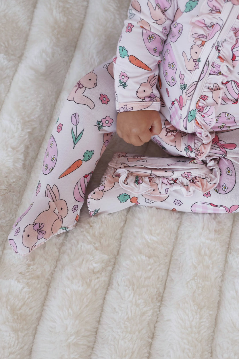 easter baby footie pajama for girls in pastel pink with bunnies, easter eggs, carrots, and flowers 