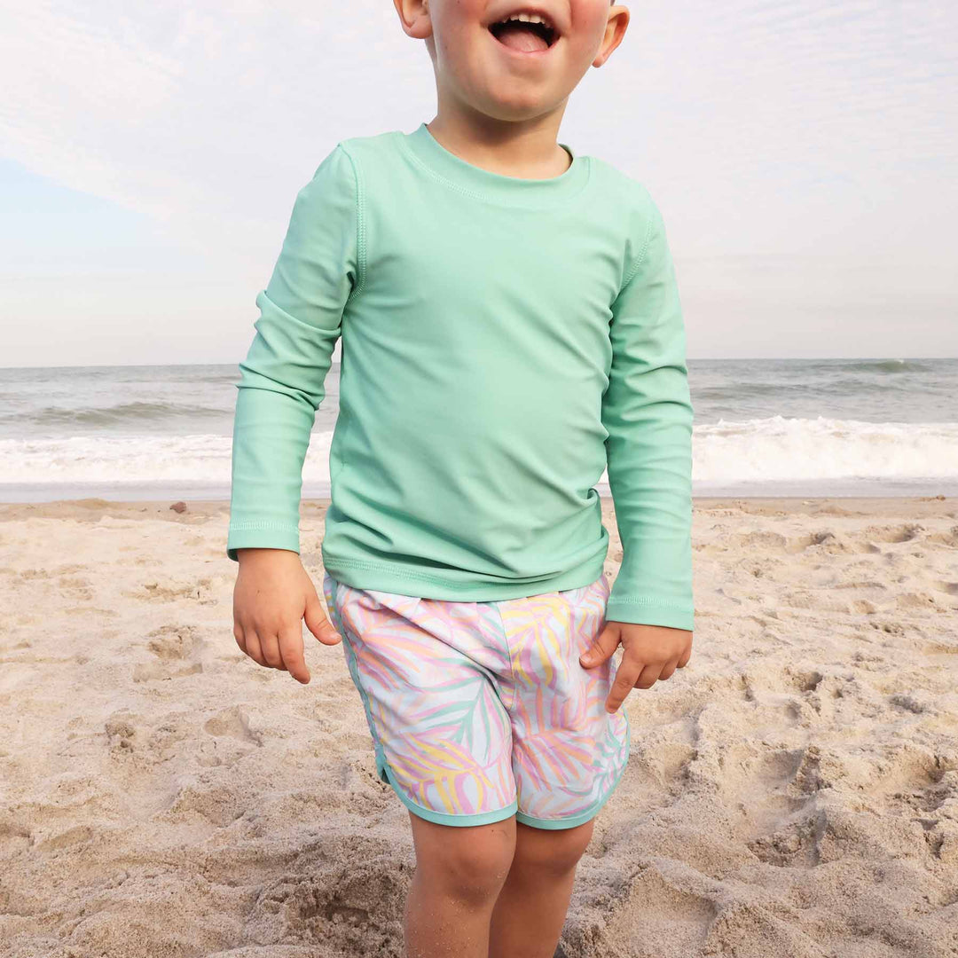 boys' swim trunks with a playful pastel palm leaves pattern and mint green trim - caden lane