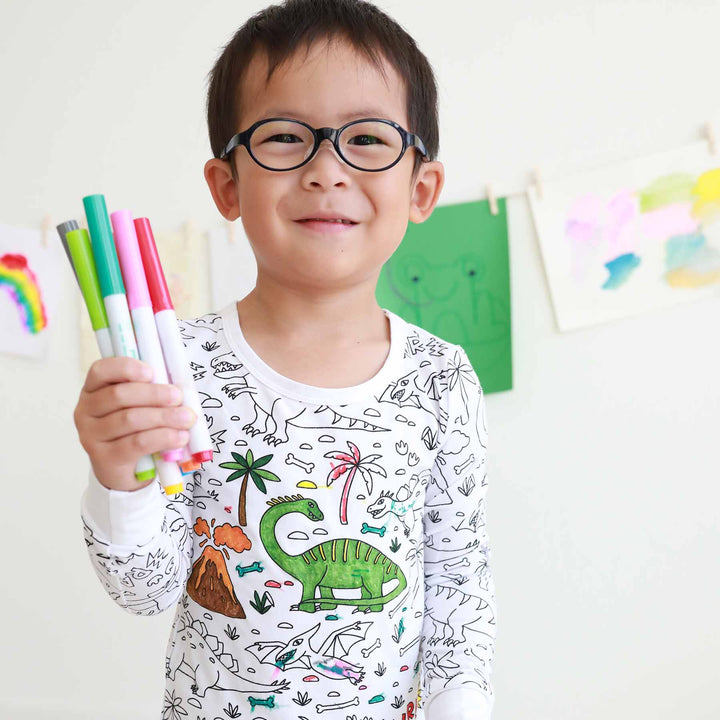 boy wearing Jurassic Playground Colorable Pajama Two Piece Set and holding markers