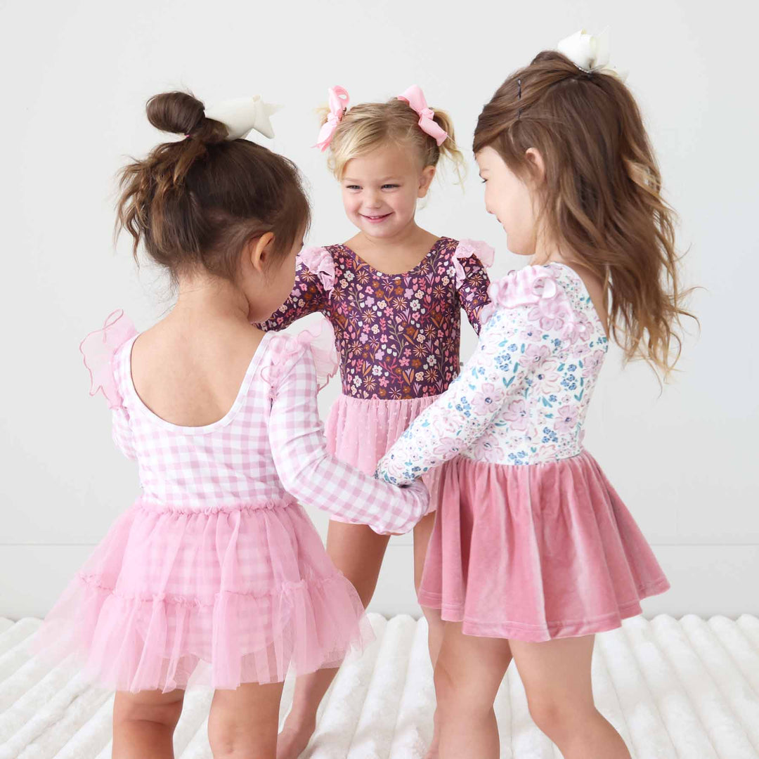 girls wearing long sleeve fall printed leotard twirling in a circle 