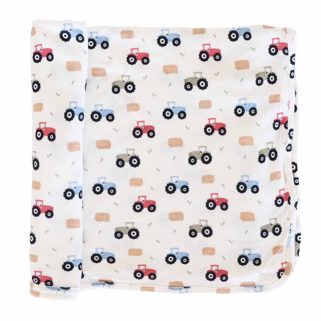 red, green and blue tractor bamboo waffle swaddle blanket with hay bales and greenery