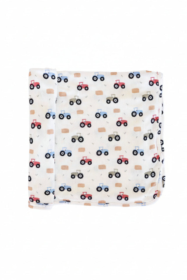 red, green and blue tractor bamboo waffle swaddle blanket with hay bales and greenery
