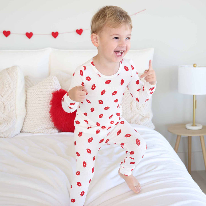 boy jumping on the bed in little kisses two piece pajama set for kids gender neutral