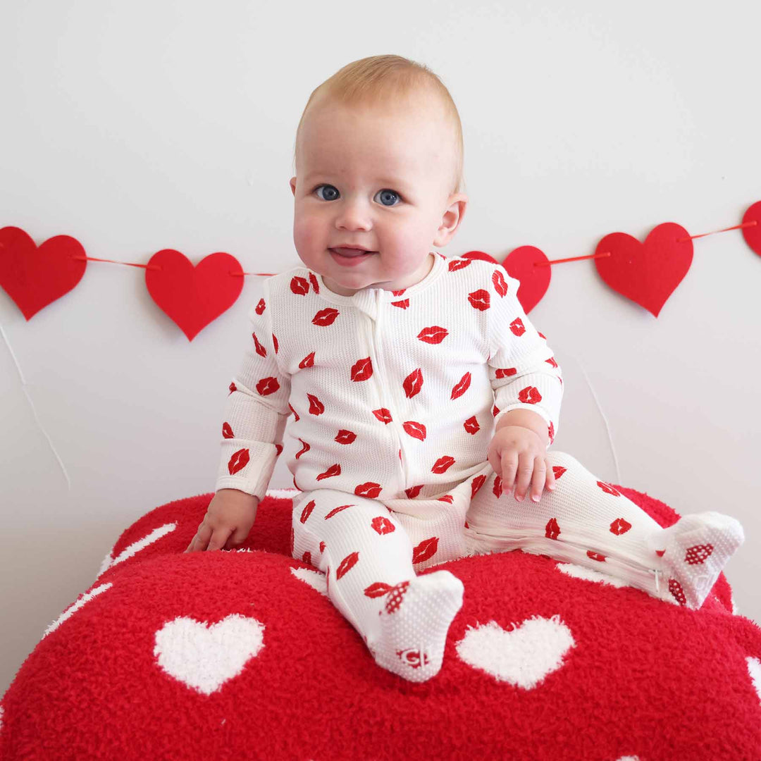 sitting baby wearing a red lip baby valentine's day footie 