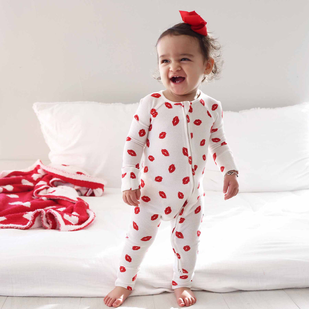 smiling baby girl in valentine's day bamboo waffle pajama romper red and white 