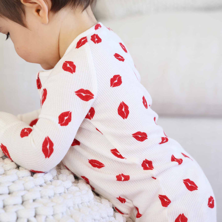 closeup of white bamboo waffle convertible zip romper pajama with red lip kisses