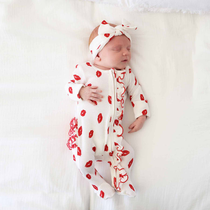 newborn baby wearing a valentine's day kiss footie with ruffles white and red 