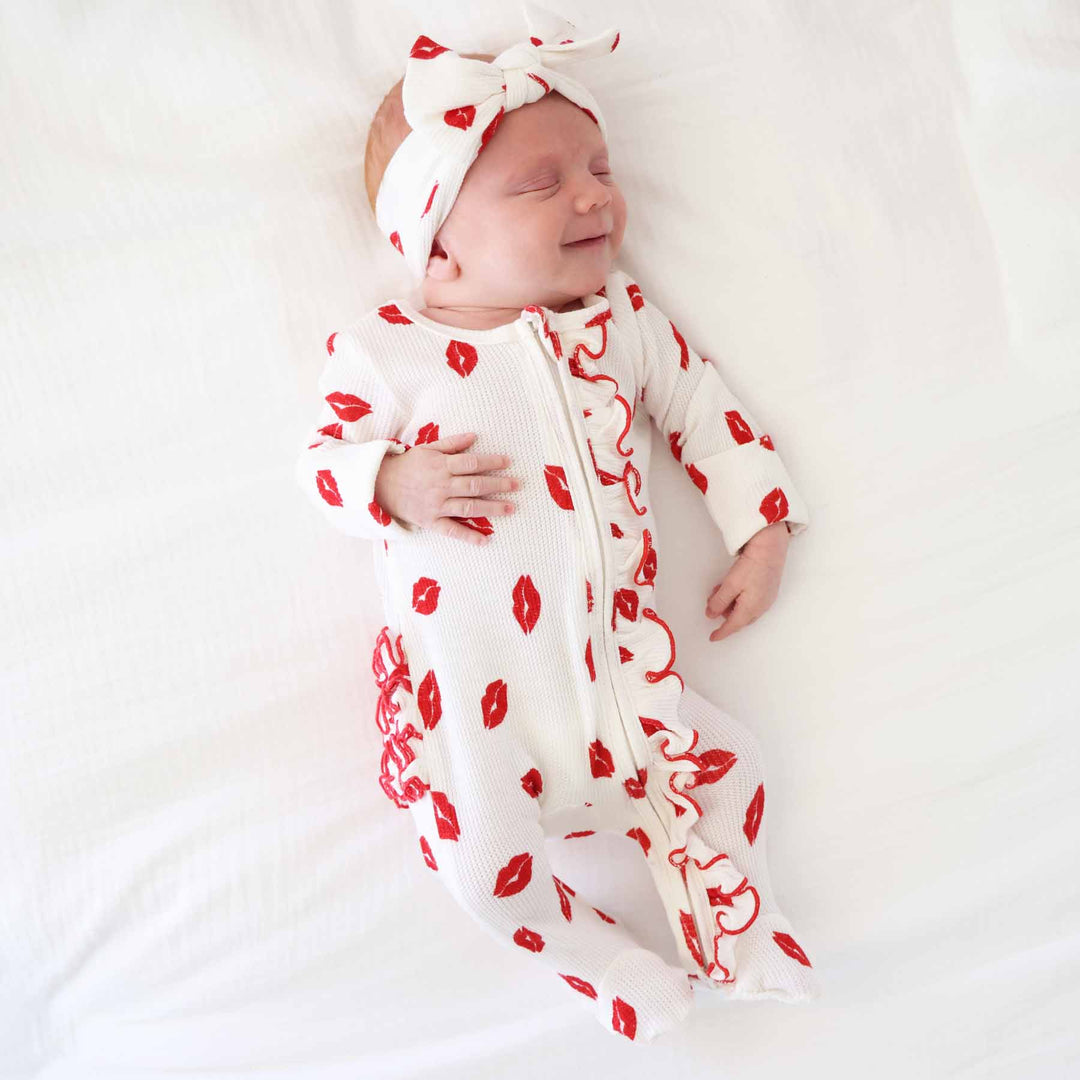 closeup of little kisses ruffle zipper footie for girls sibling matching valentine's day pajamas 