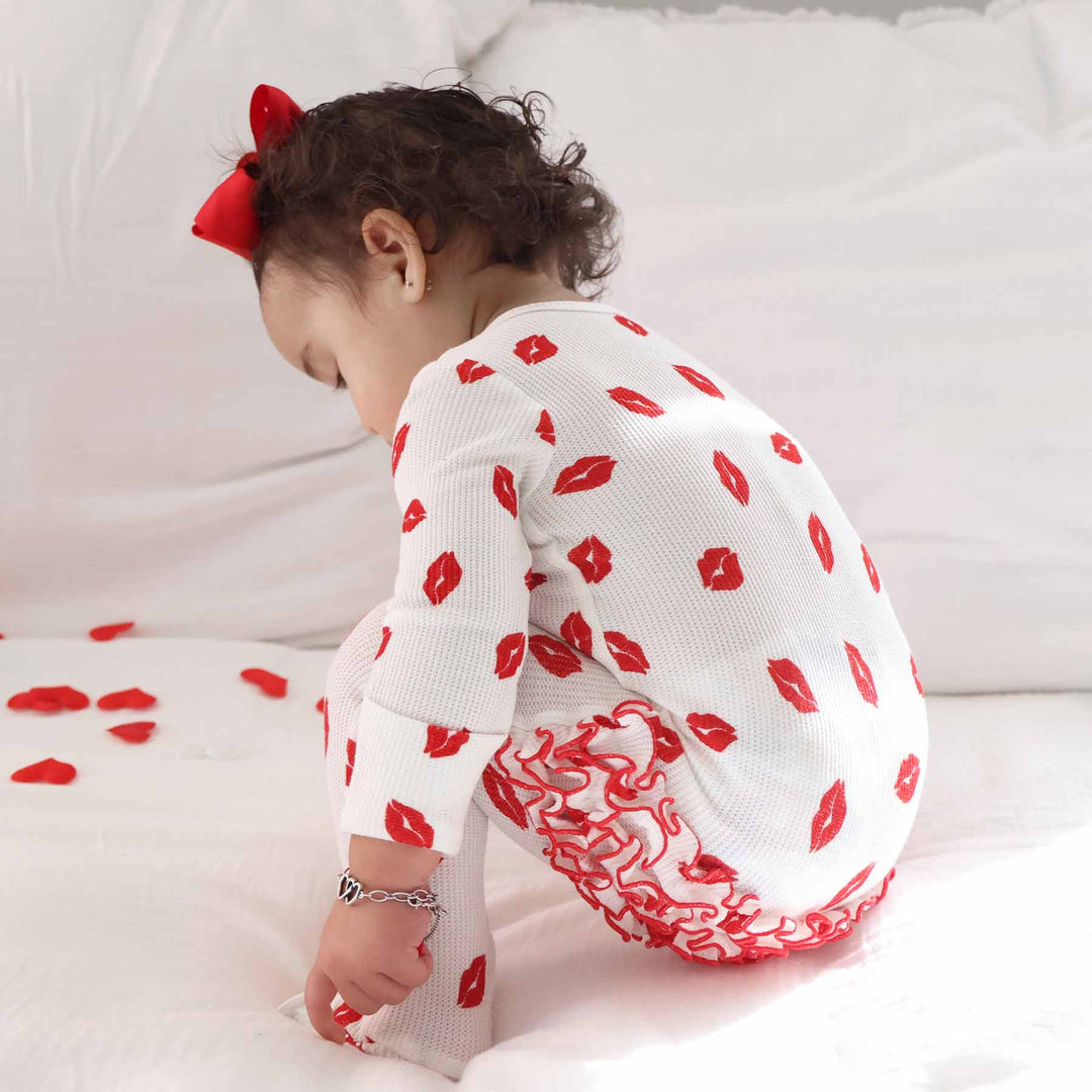baby girl squatting down in sibling matching valentine's day ruffle footie pajama 