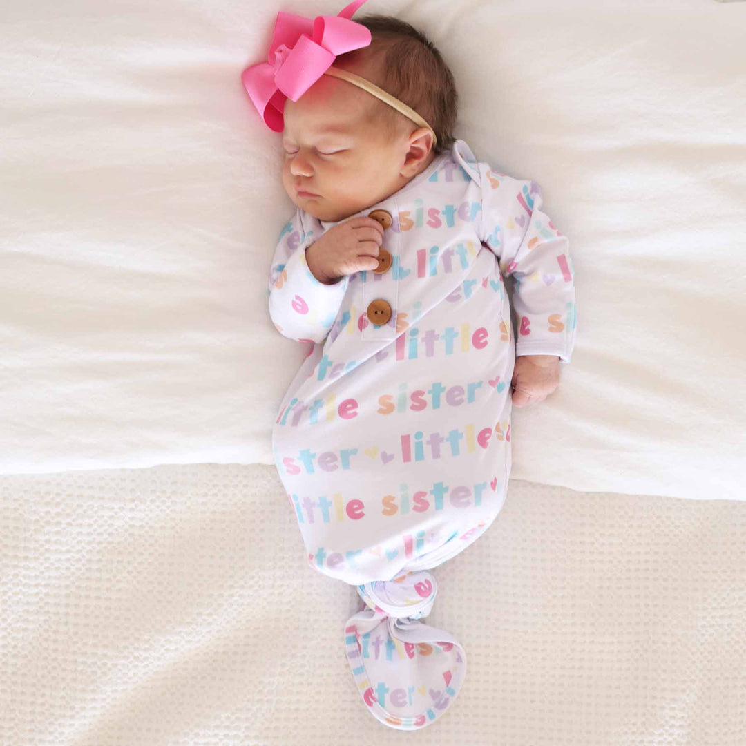 newborn wearing little sister knot gown with pink bow headband